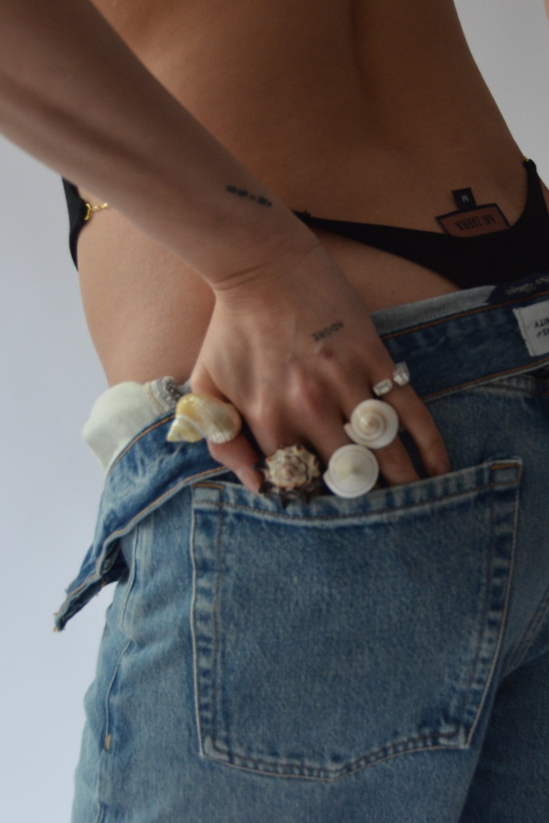 Person wearing blue jeans with lots of shell rings with a white background