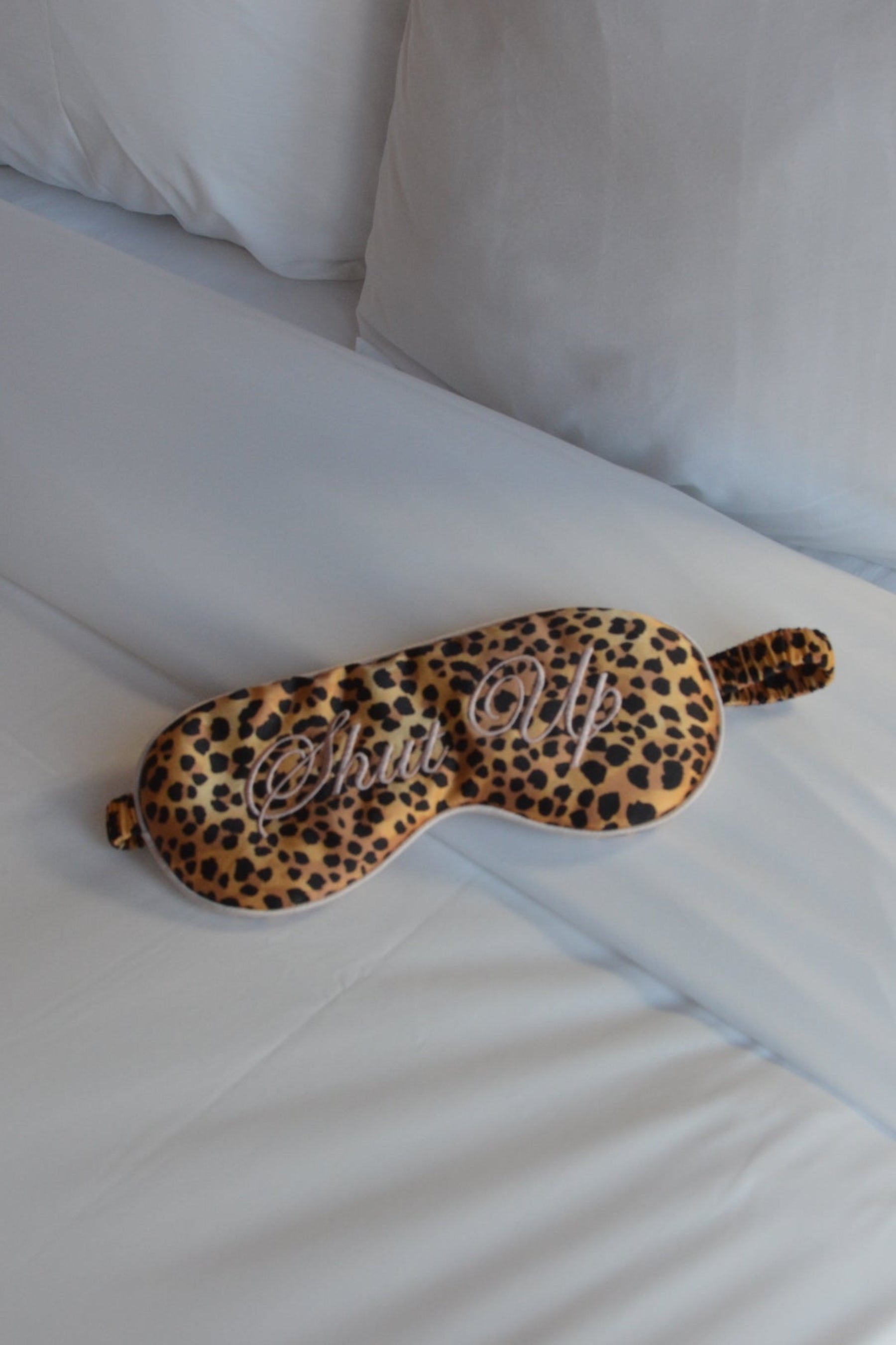 Leopard print eye mask on a white bed