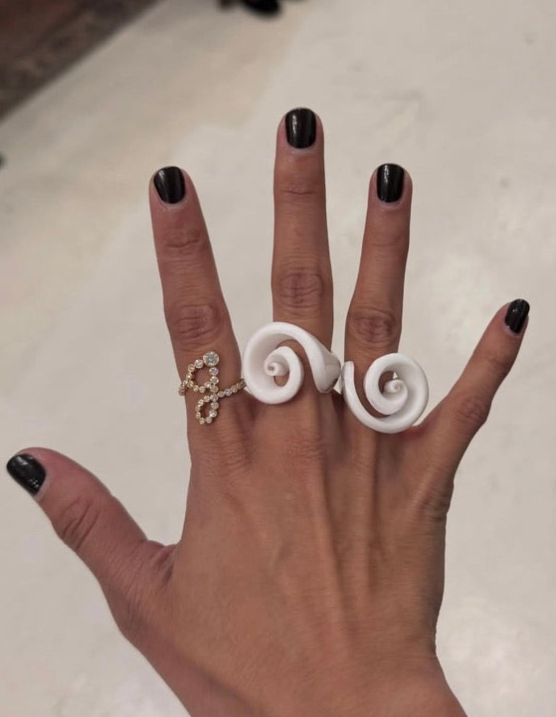 Hand wearing two spiral rings on a blurred background