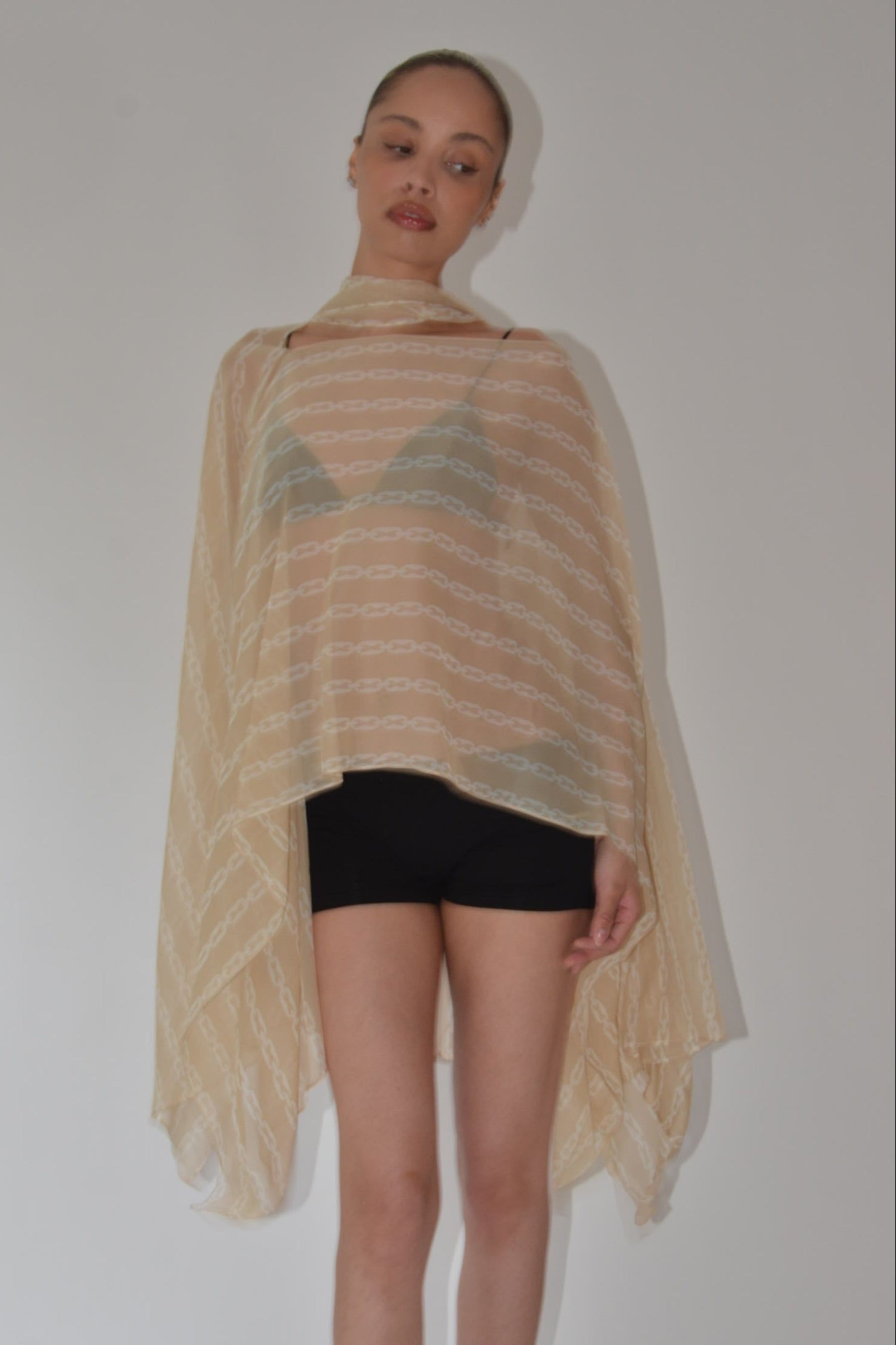 Person wearing a patterned beige garment over a plain background
