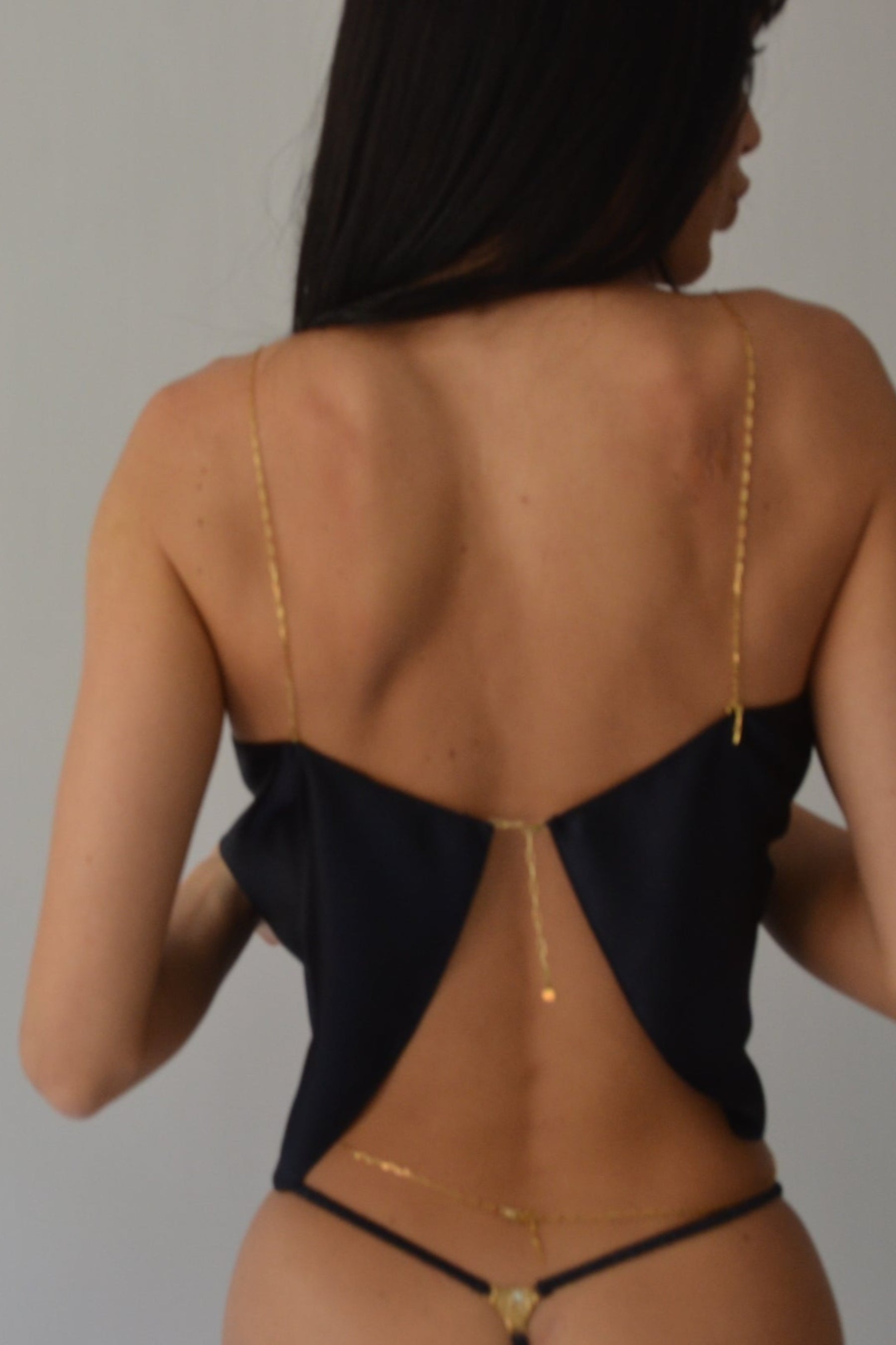 Woman wearing a navy top with gold accents against a plain background