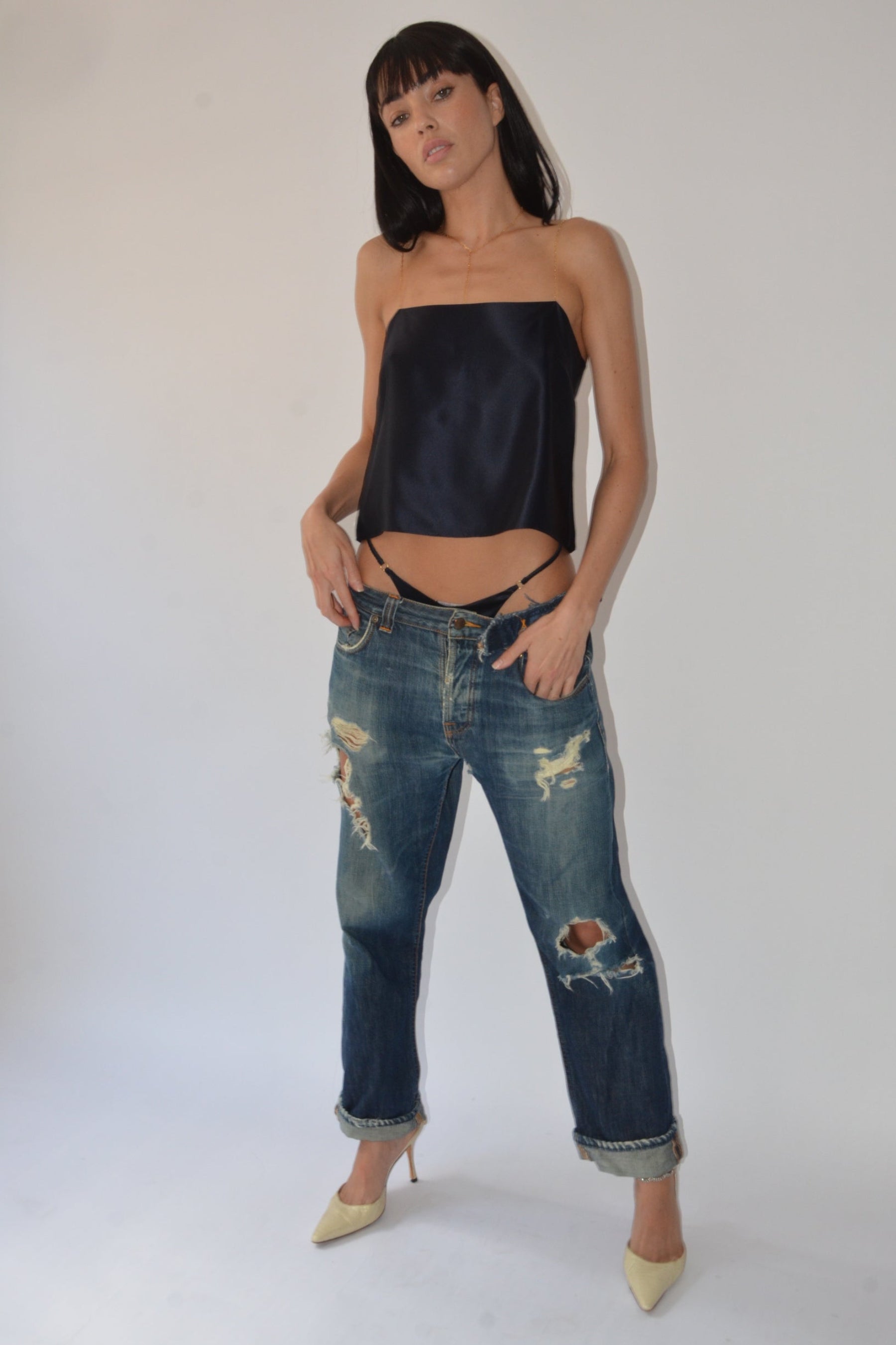 Person wearing distressed blue jeans and a navy top on a white background
