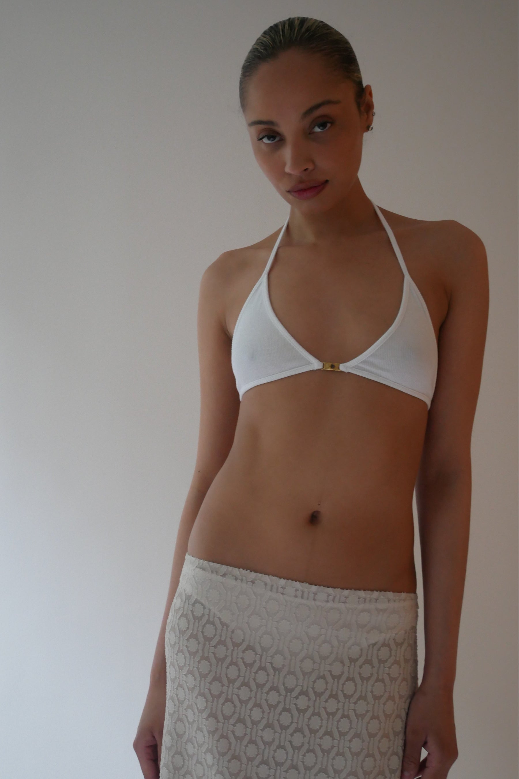 Woman wearing a white bikini top with a plain background