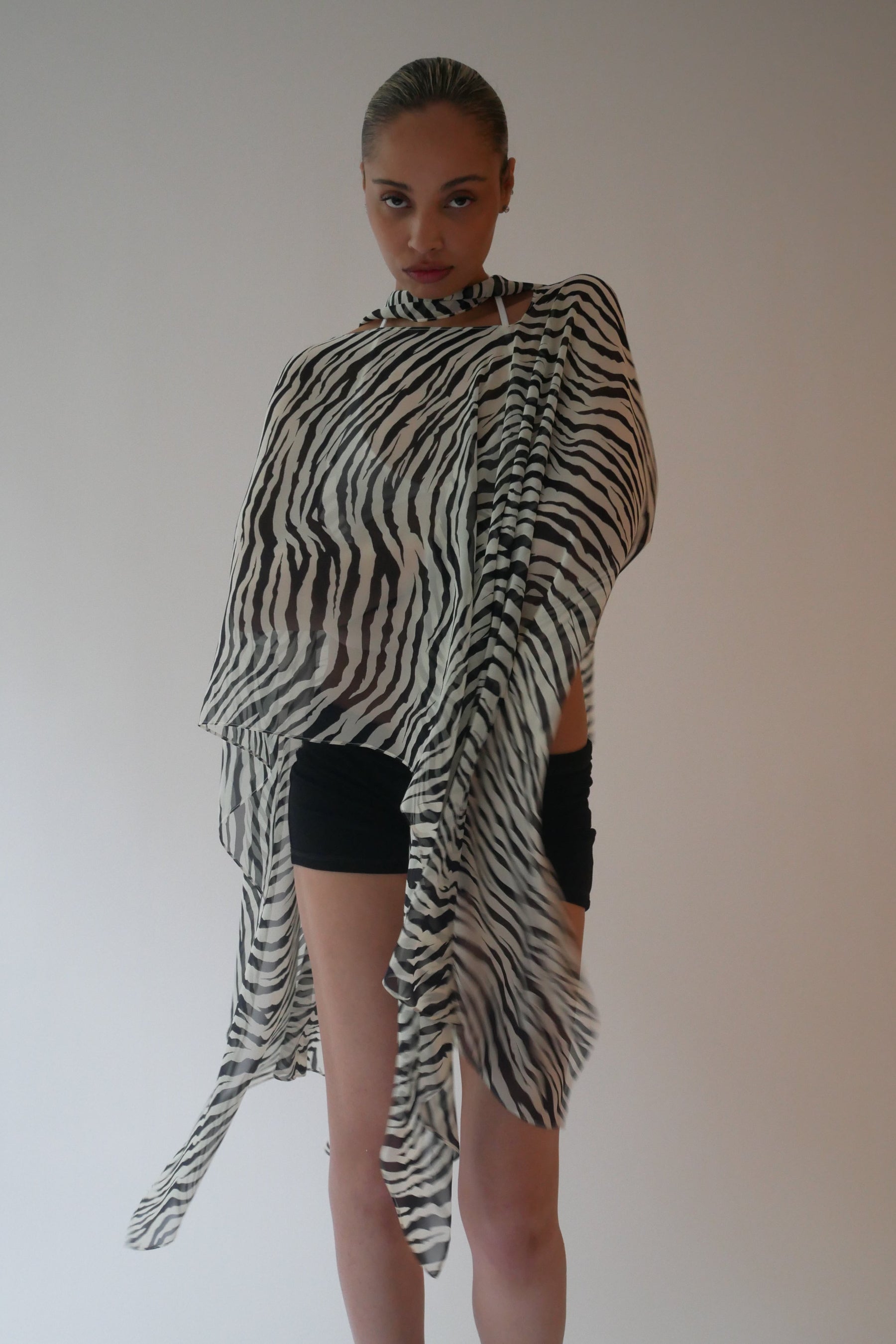 Person wearing a zebra-striped shawl against a plain background