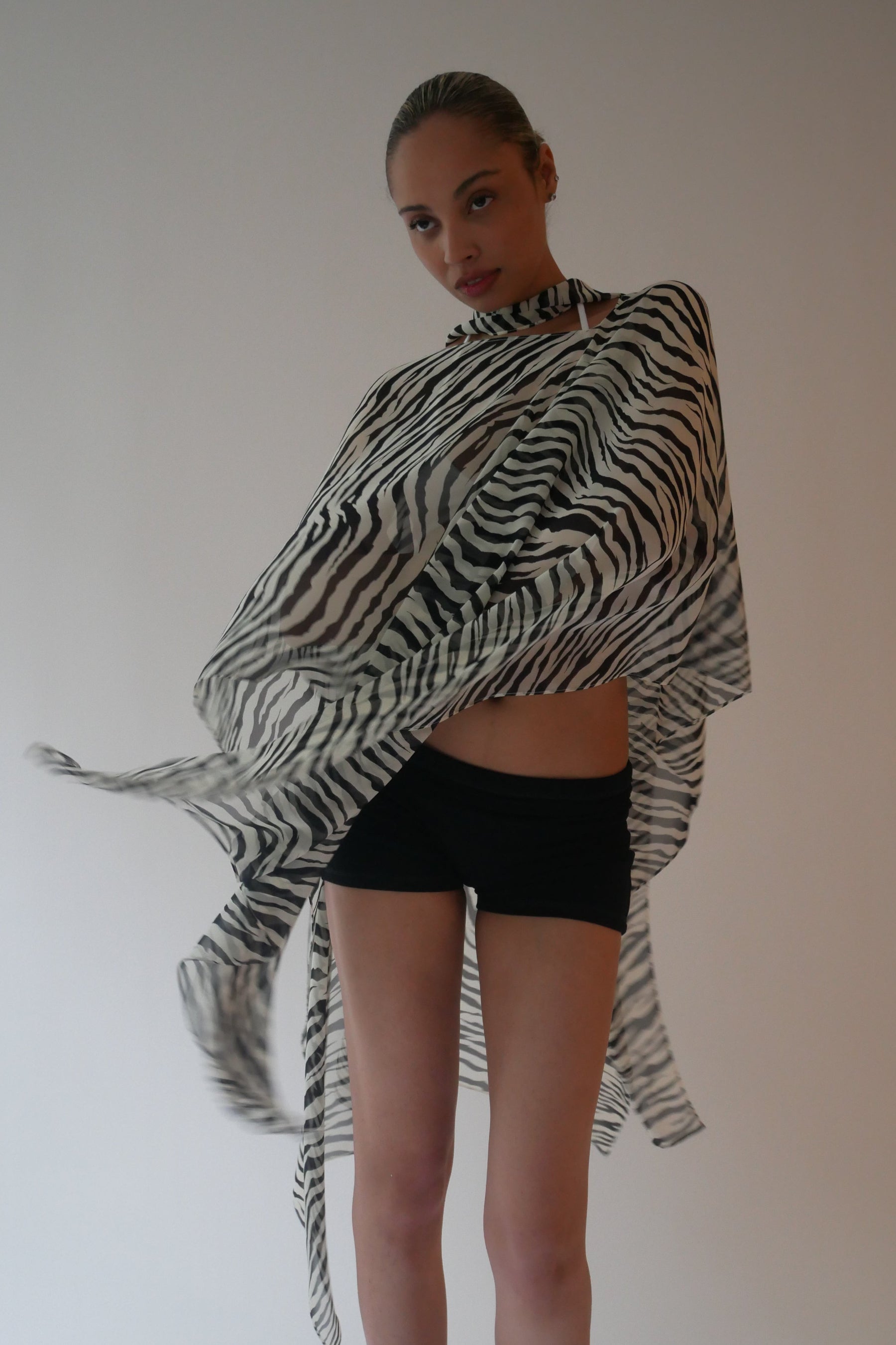 Person wearing a zebra-patterned shawl over a plain background